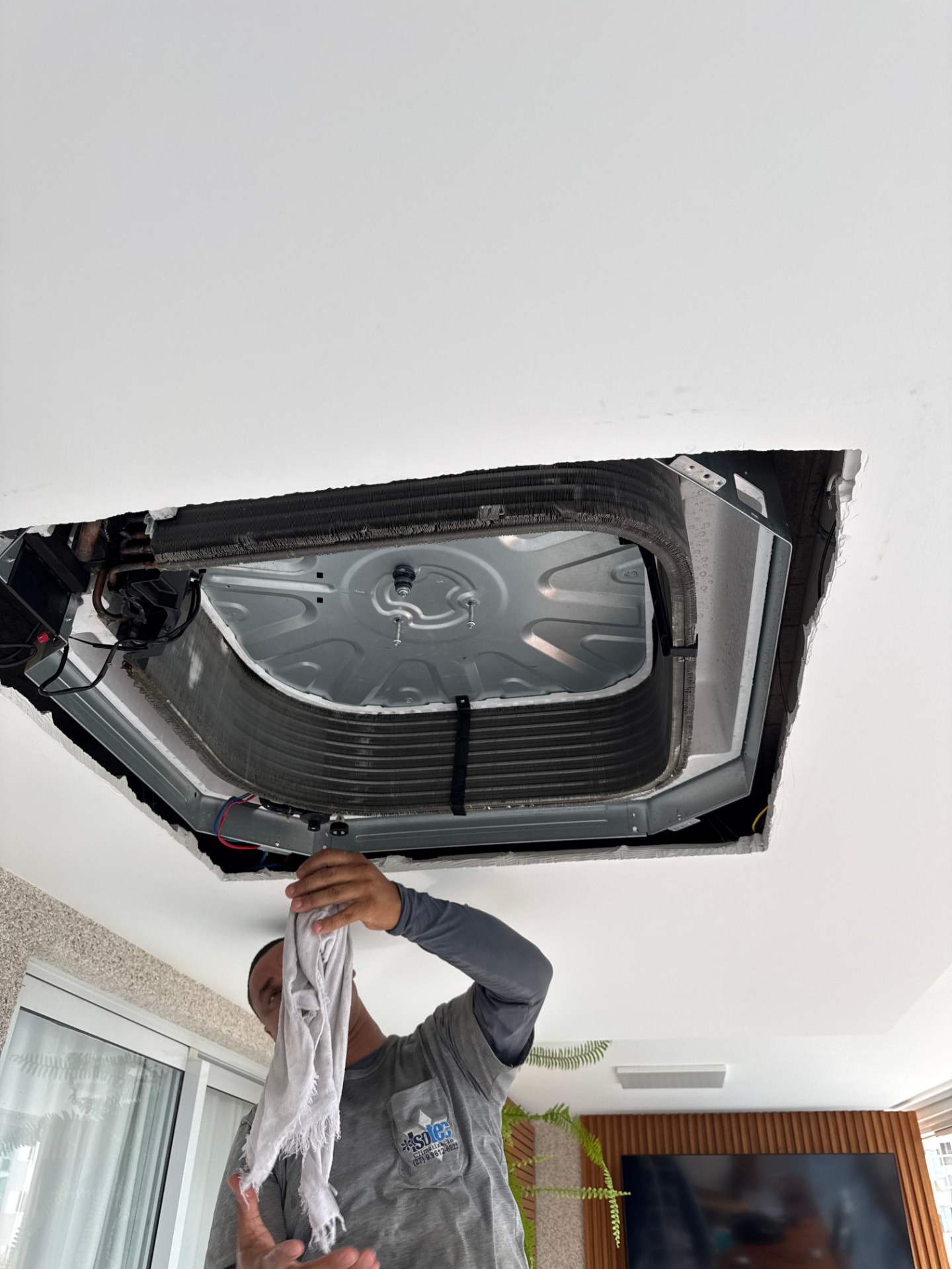 Serviço em unidade de climatização instalada no teto de um ambiente