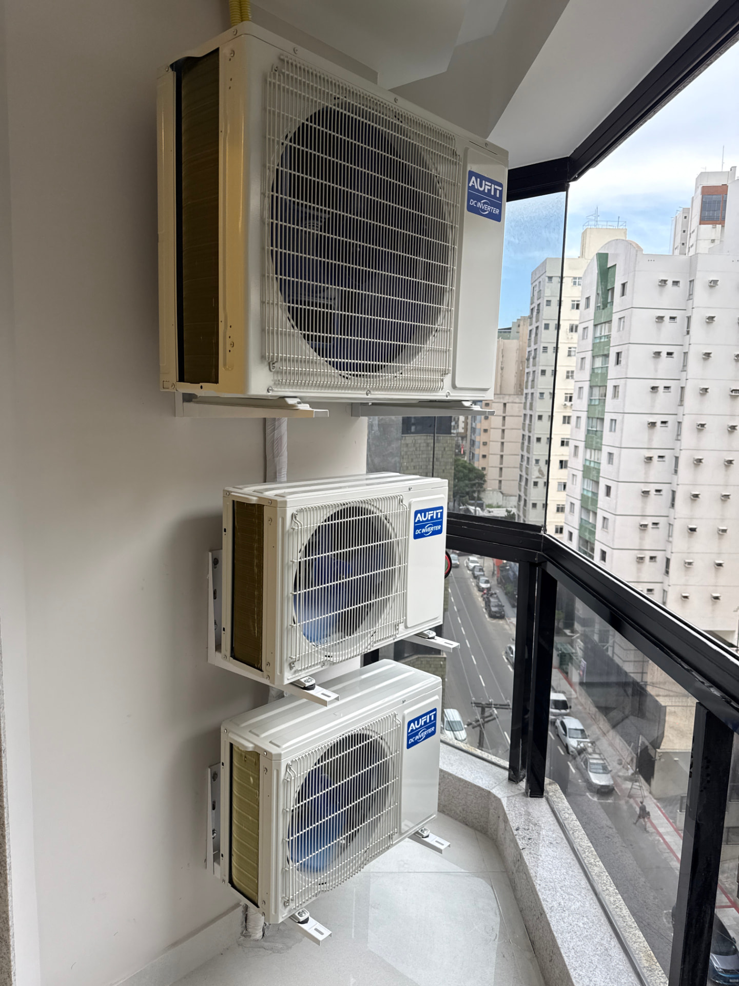 Três condensadoras instaladas em suportes na área externa de um apartamento