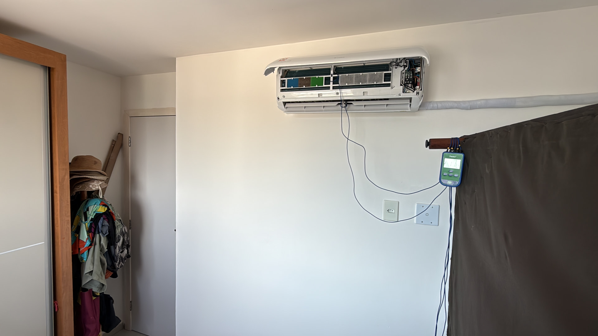 Medição técnica durante manutenção de ar-condicionado em quarto residencial